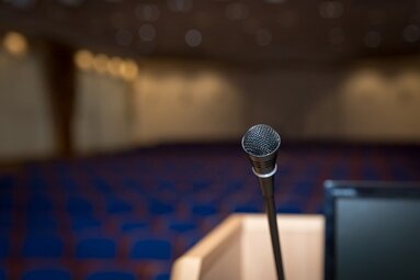 Mikrofon auf einem Rednerpult in einem leeren Konferenzraum mit unscharfen Sitzreihen | © Pixabay