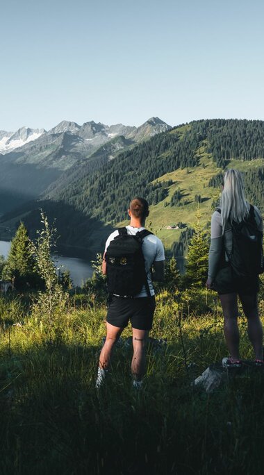 Zwei Wanderer genießen den Blick auf einen Stausee und Gletscher in den Alpen. | © Ferienregion Nationalpark Hohe Tauern - Daniel Kogler